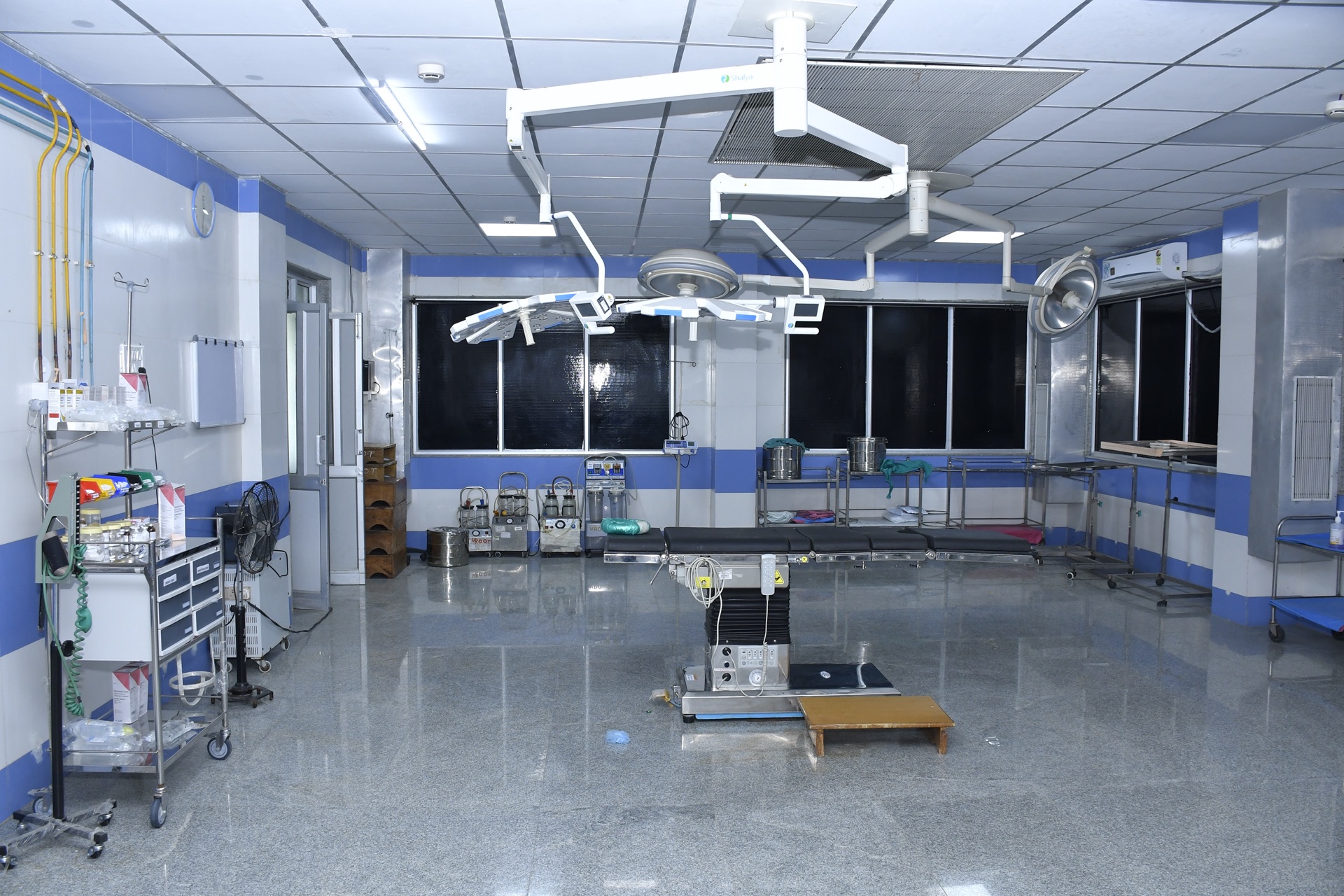 Clean operating theatre with blue accent walls, ceiling-mounted surgical lights and sterile field ready