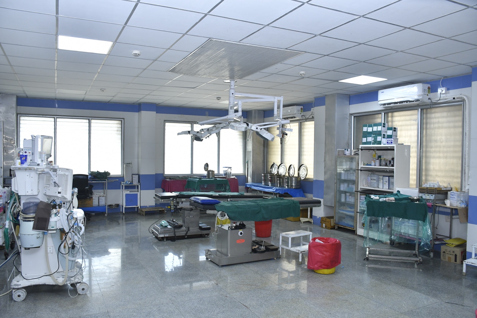 Fully equipped operating theatre with surgical lights, anaesthesia machine and instrument trolleys